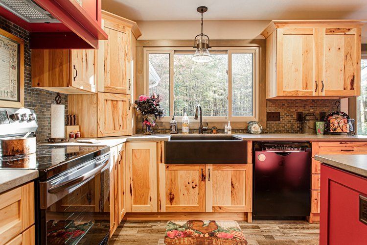 Wooden kitchen with black appliances, sink, and red accents.