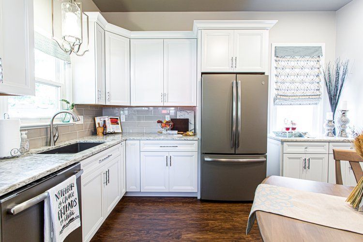 White kitchen with stainless steel appliances, granite countertops, and dark wood floors.