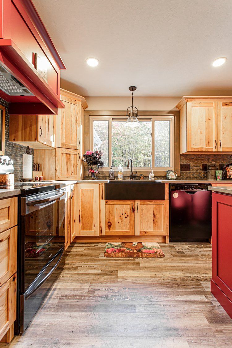 Kitchen with natural wood cabinets, red accents, and a black farmhouse sink.