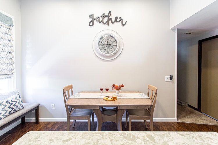 Dining area with a table set for two, a clock, and a 