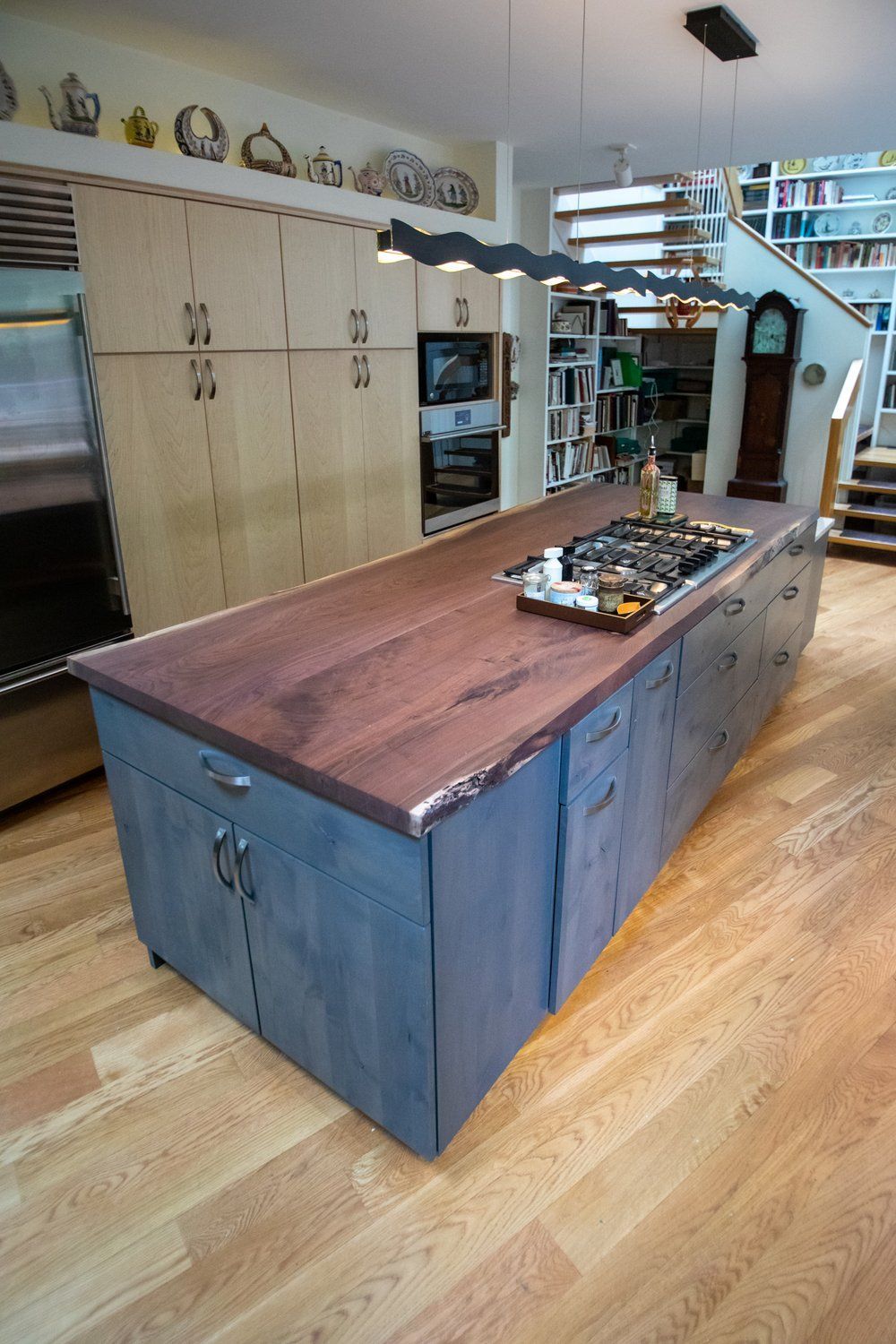 Kitchen island with blue cabinets, dark wood countertop, and built-in stovetop.