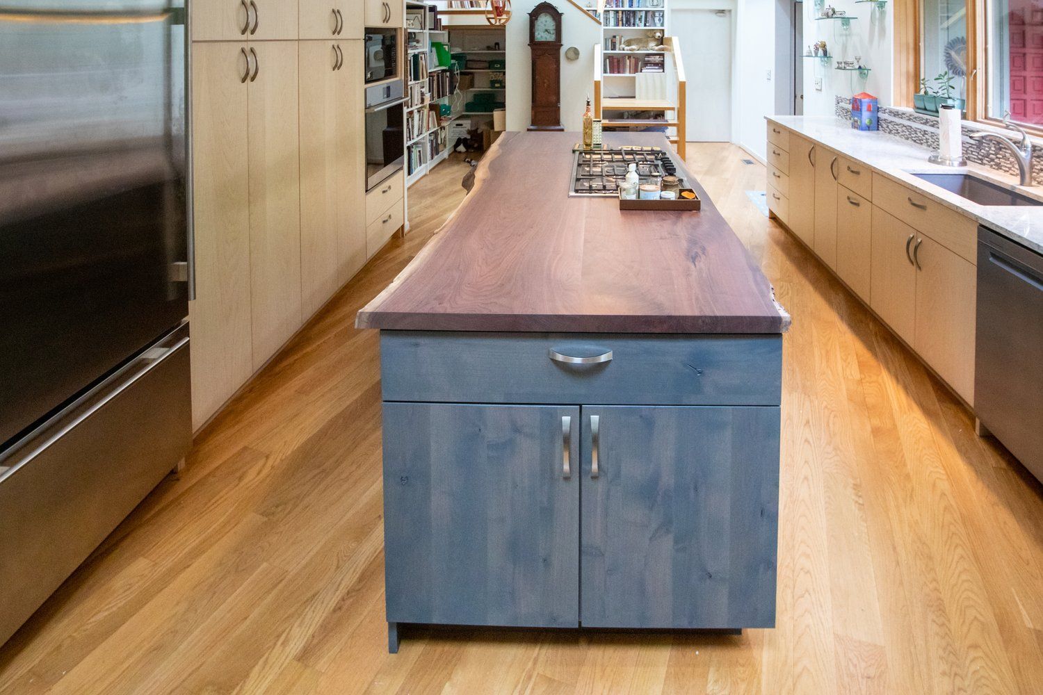 Kitchen with blue island, wooden countertop, oven, stainless steel appliances, and wooden floor.