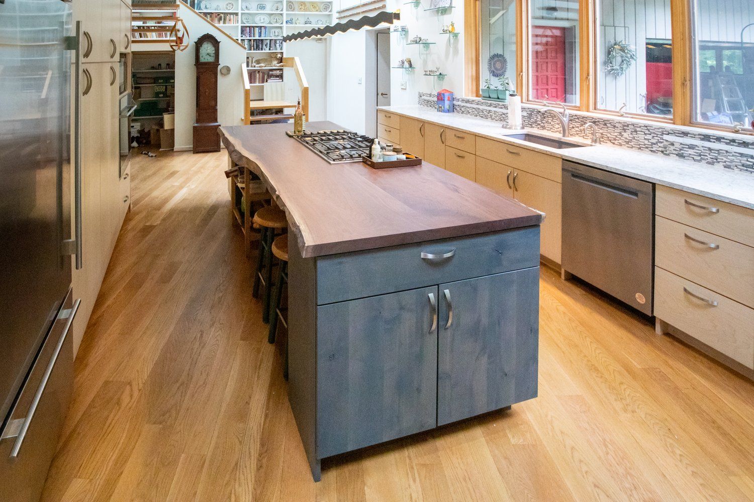 Kitchen with wood floors, island with cooktop, and light-colored cabinetry.