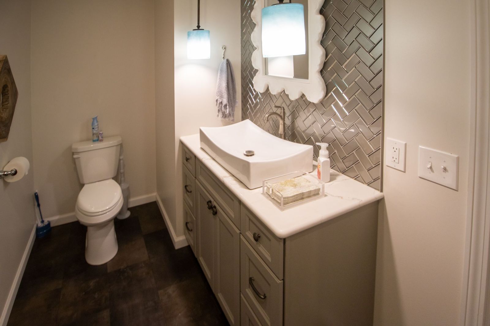 Small bathroom with a toilet, vanity with vessel sink, and decorative backsplash.
