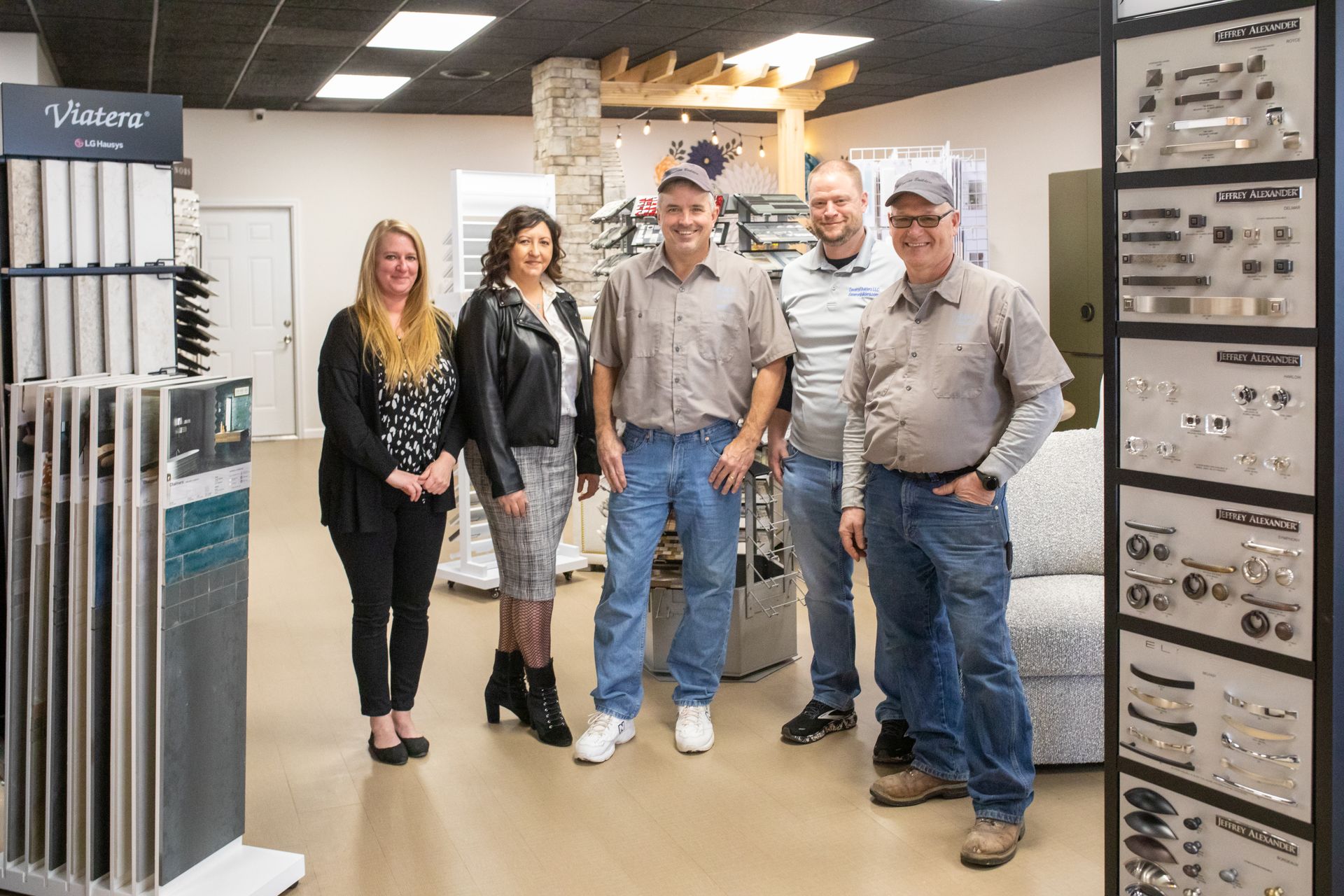 Five people stand in a showroom with displays of hardware and samples.