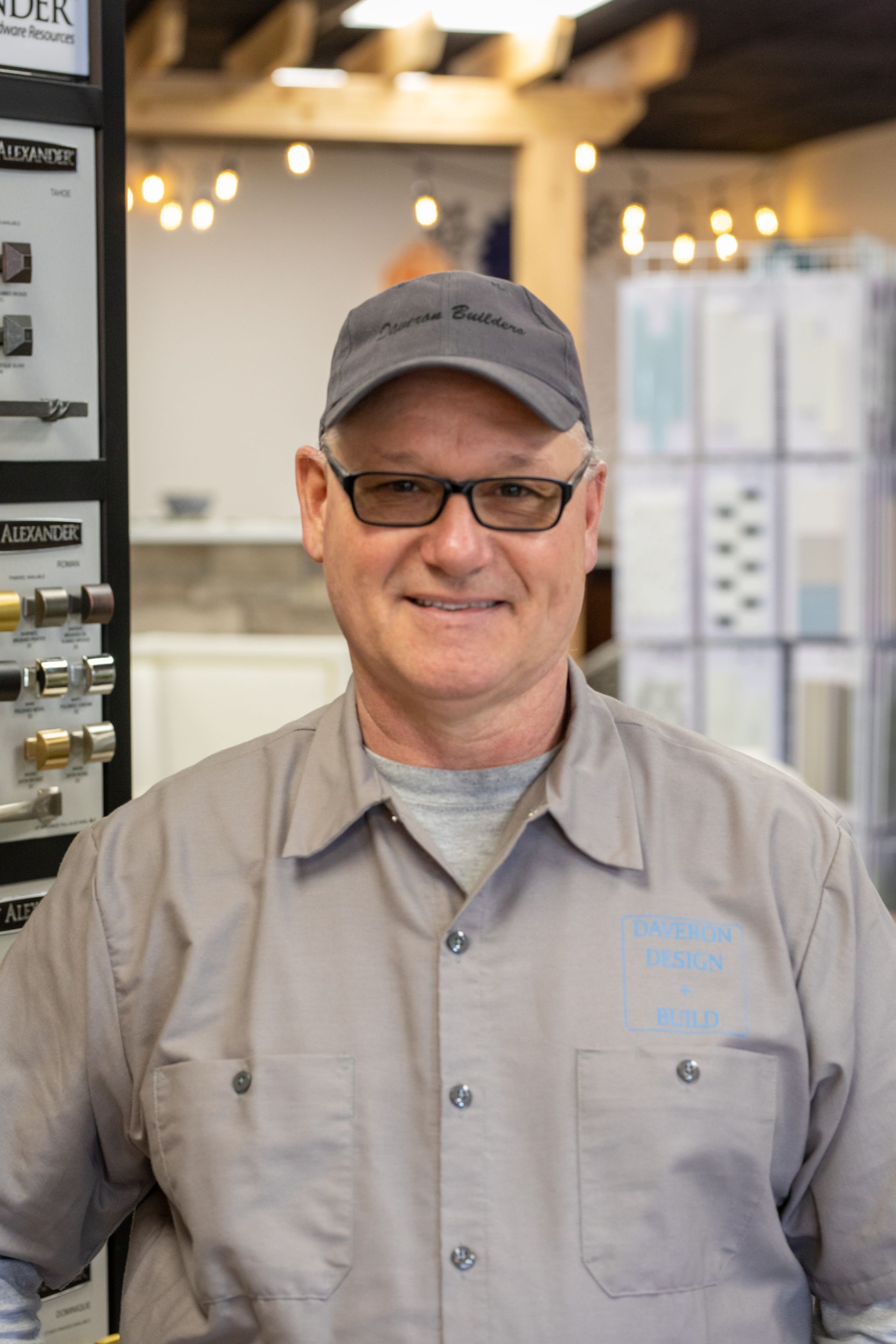 Man wearing glasses and hat, smiling in a store with hardware displays.