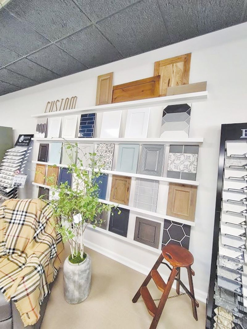 Cabinetry display with samples on a white shelf. A couch with plaid blanket and a step stool are nearby.