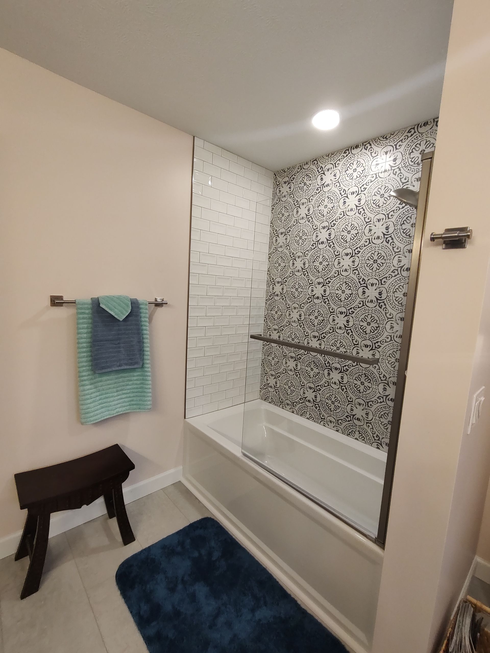 Bathroom with bathtub and shower, dark blue rug, and pink walls.