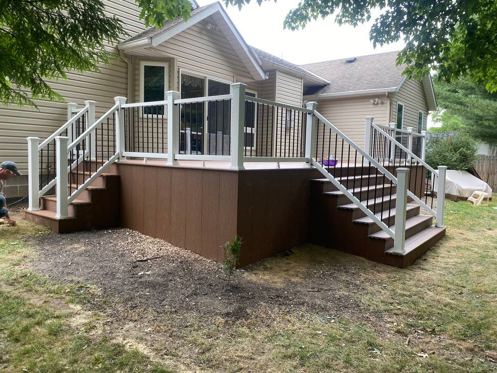 Brown composite deck with white and black railings, steps down to a yard.