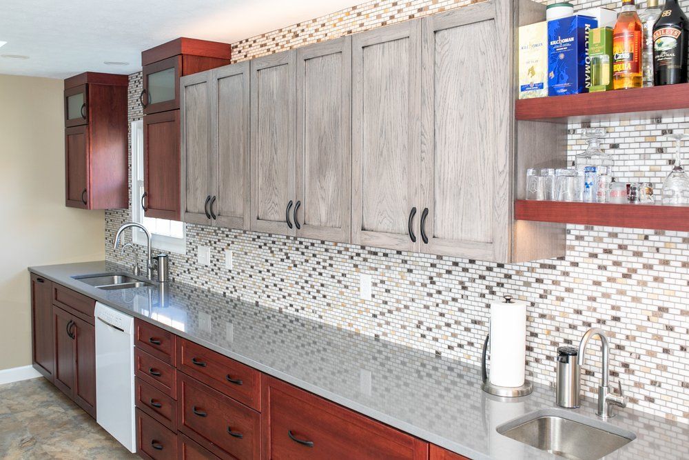 Wet bar with gray countertop, dark wood cabinets, and mosaic tile backsplash.