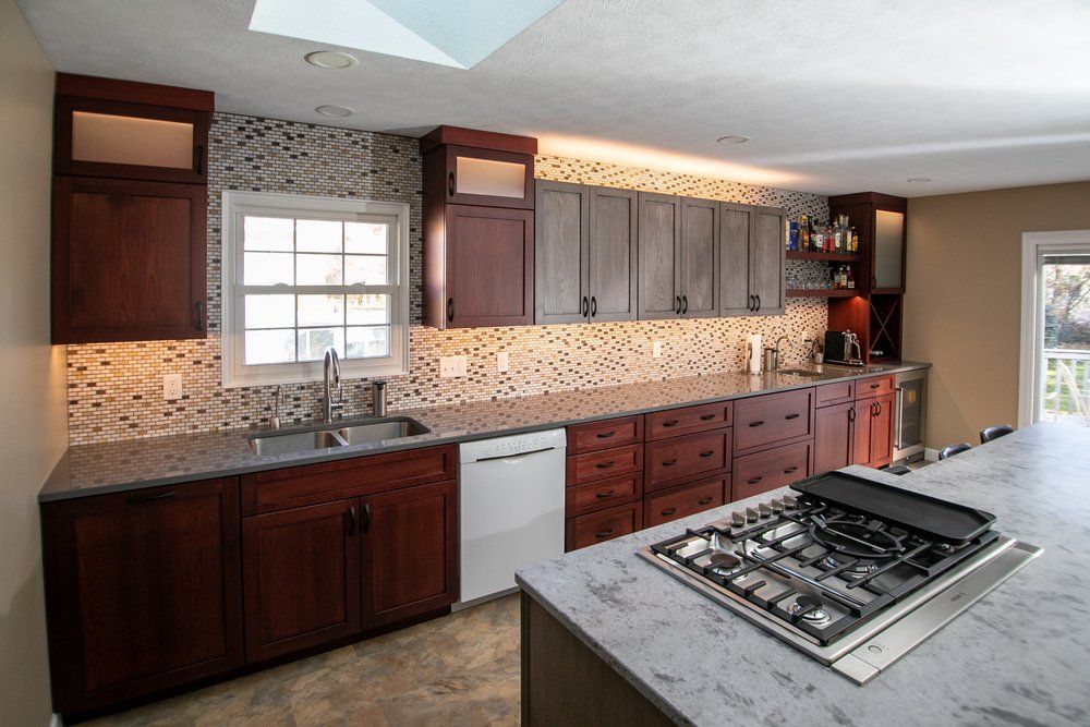 Modern kitchen with dark wood cabinets, granite countertops, and mosaic backsplash.