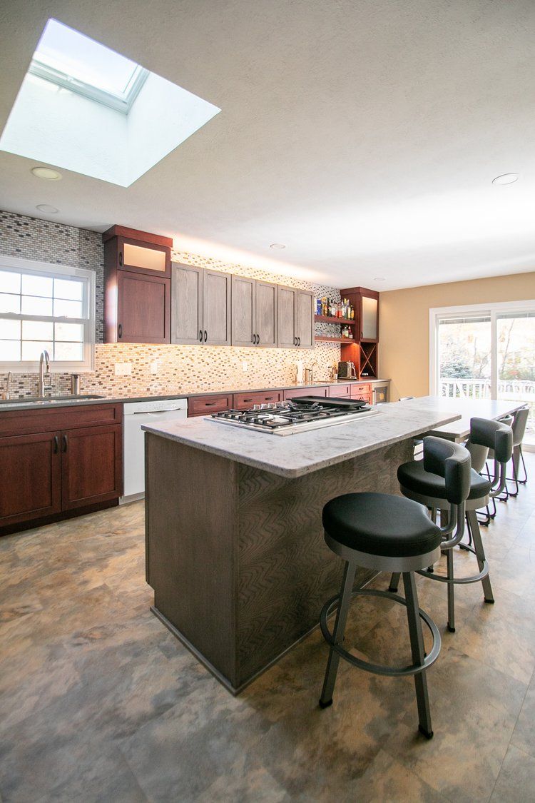 Modern kitchen with island, seating, and skylight. Gray and brown tones.