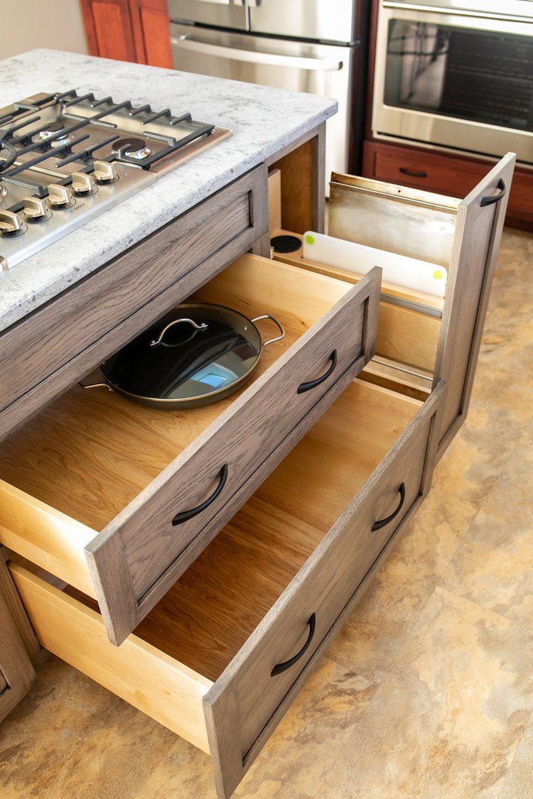 Kitchen island with partially opened wooden drawers, holding cookware.