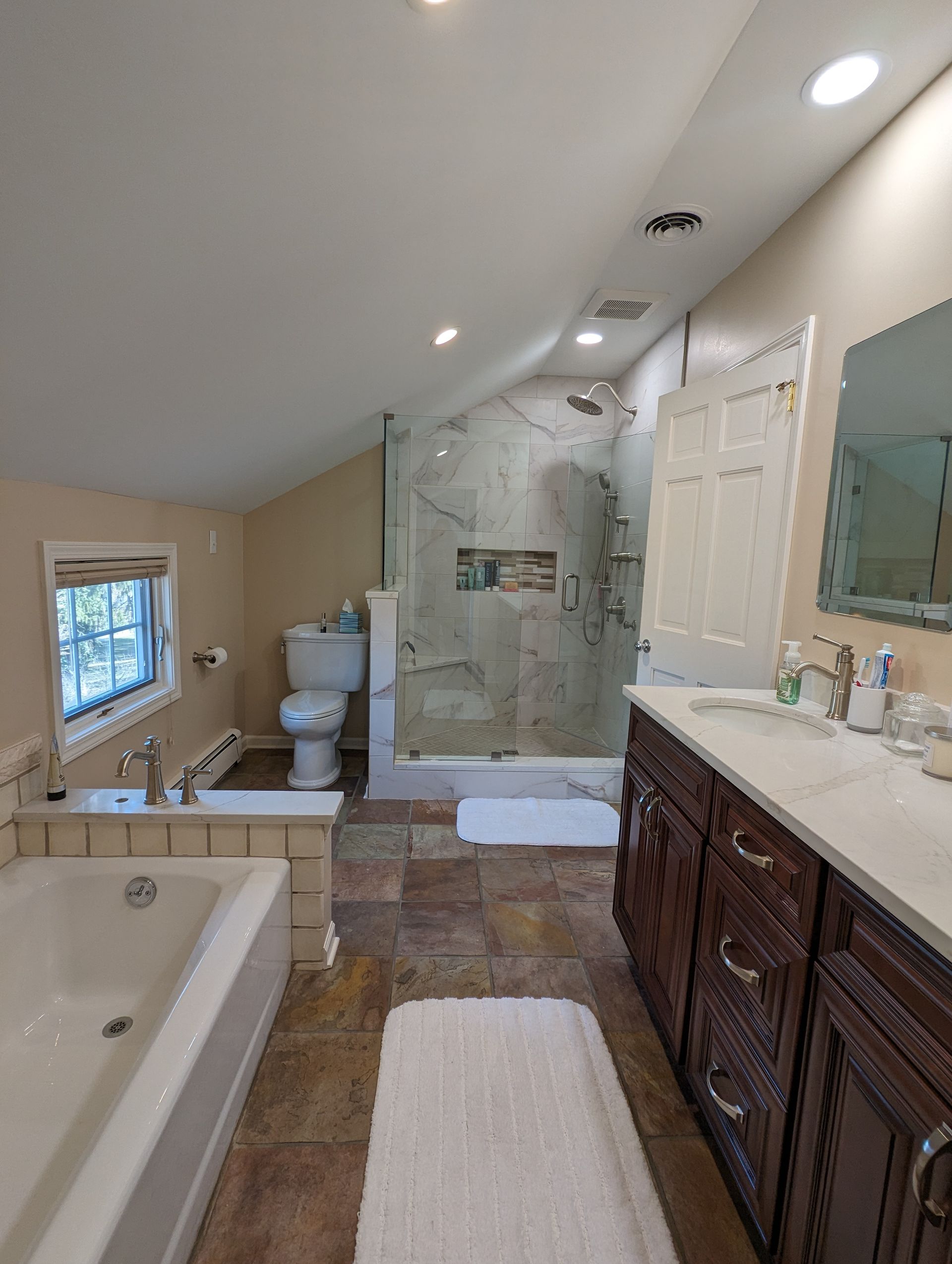 Bathroom with a jacuzzi tub, toilet, and glass shower. Dark wood vanity and beige walls.