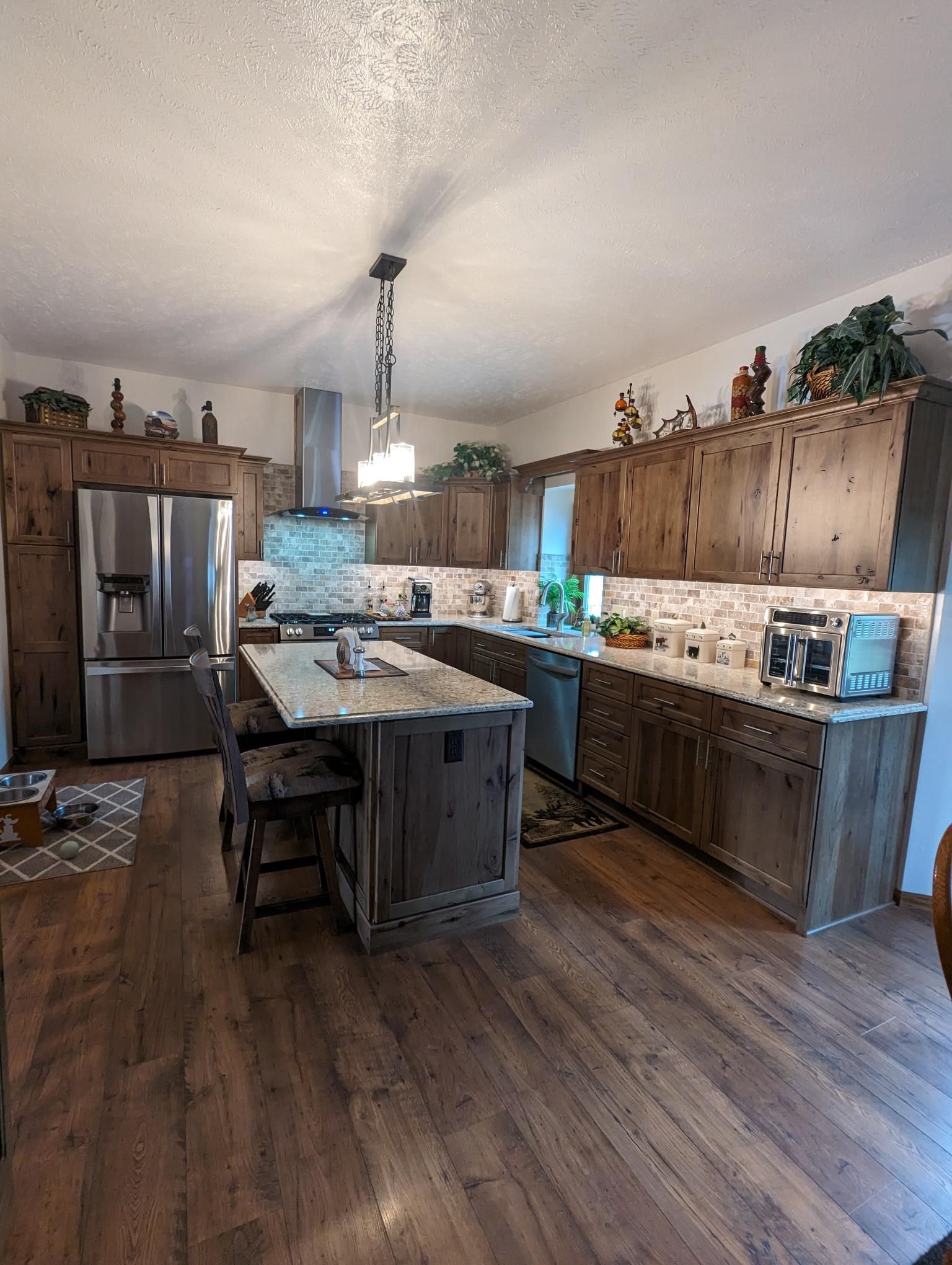 Rustic kitchen with wood cabinets, stainless steel appliances, and island.