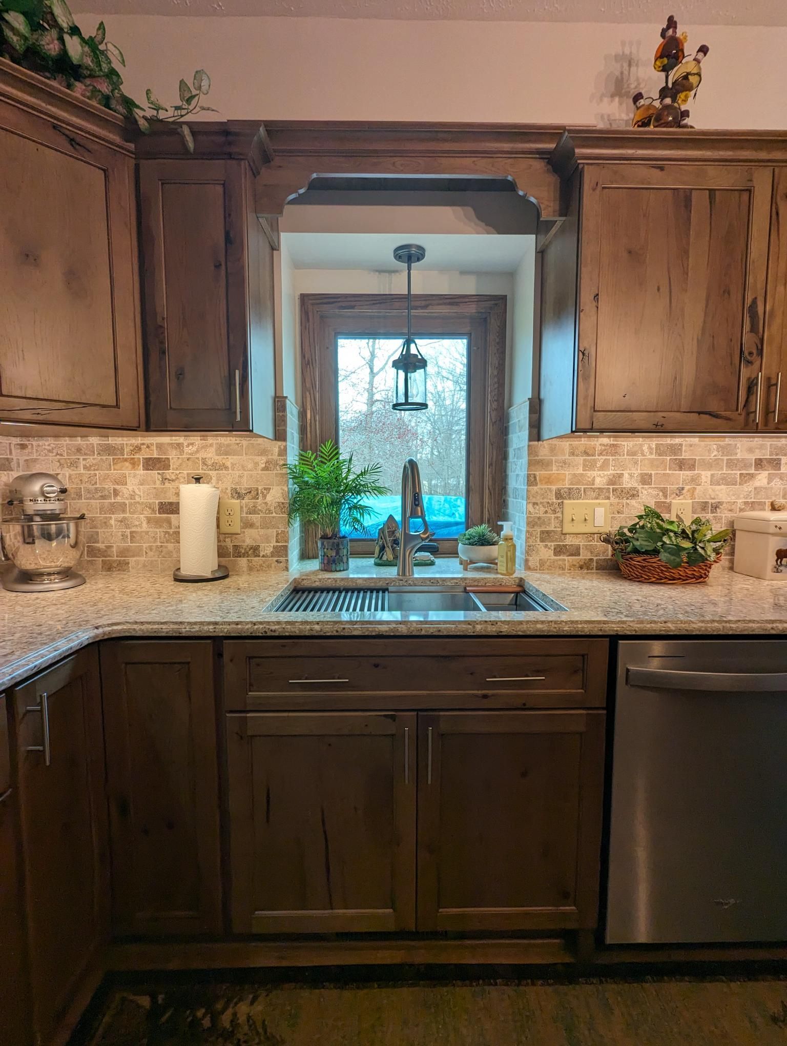 Kitchen with brown cabinets, granite countertops, and a window above the sink.