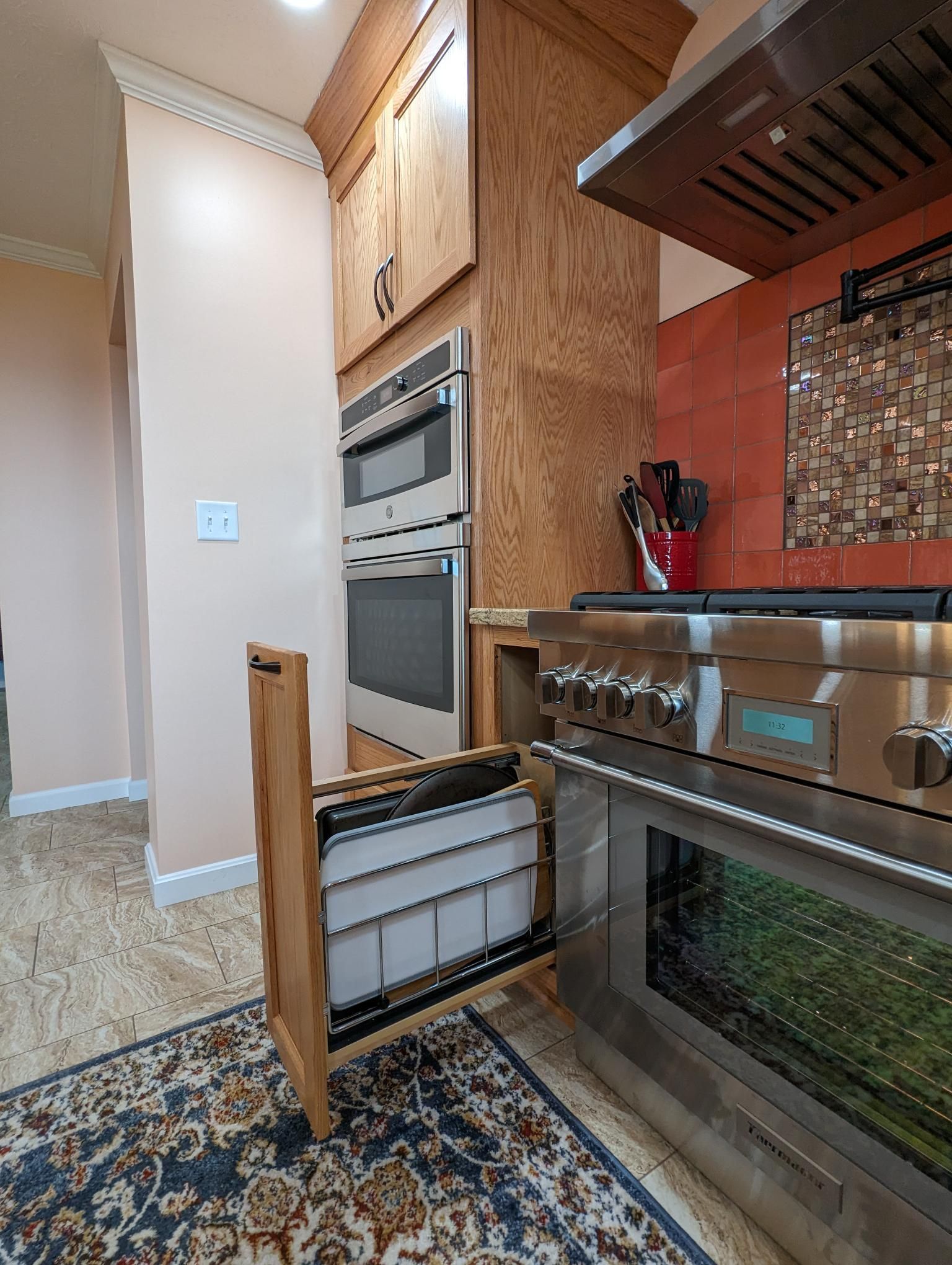 Kitchen with oven, cabinets, and a pull-out storage drawer partially open. Beige and brown tones.