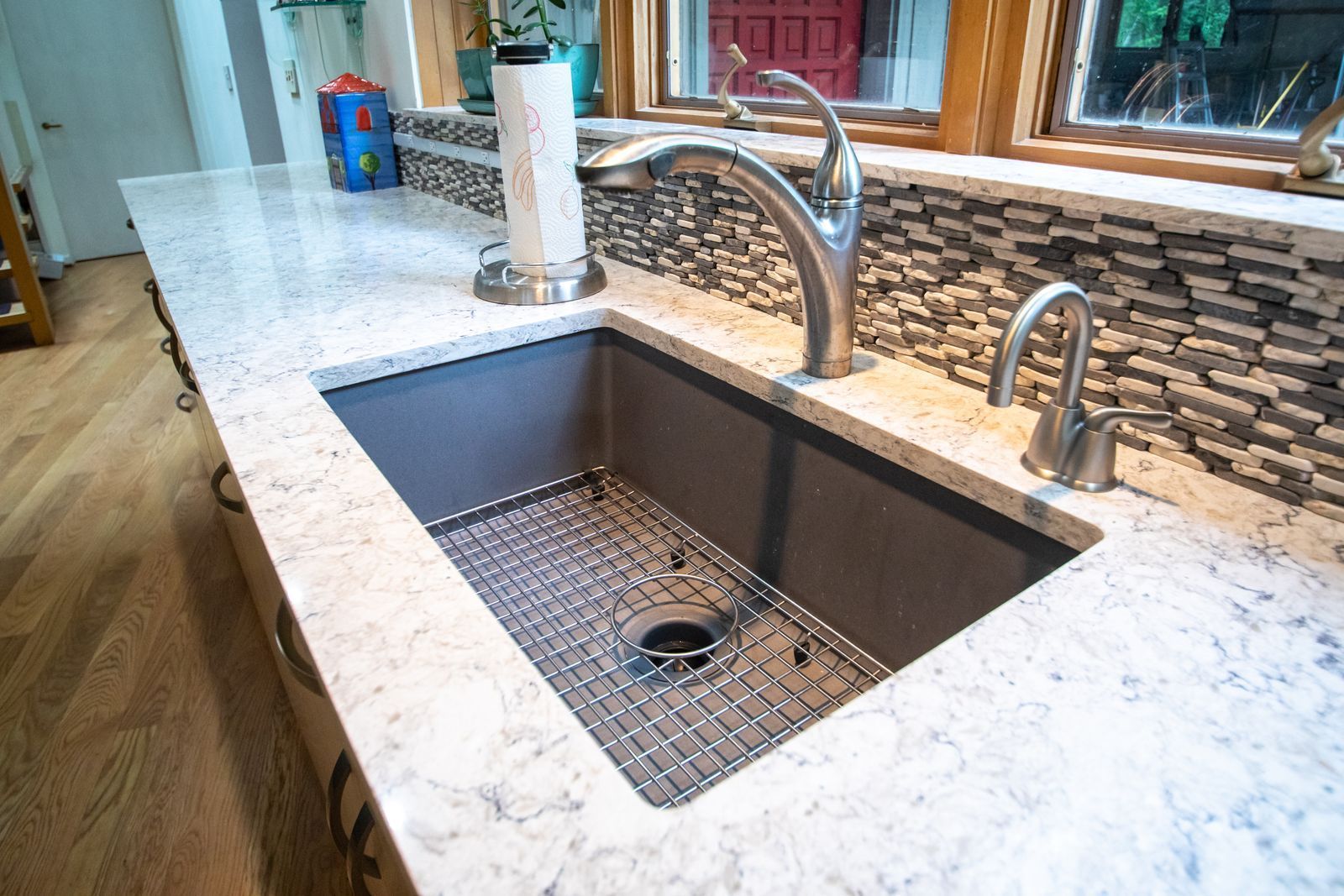 Stainless steel kitchen sink with faucet, granite countertop, and mosaic tile backsplash.
