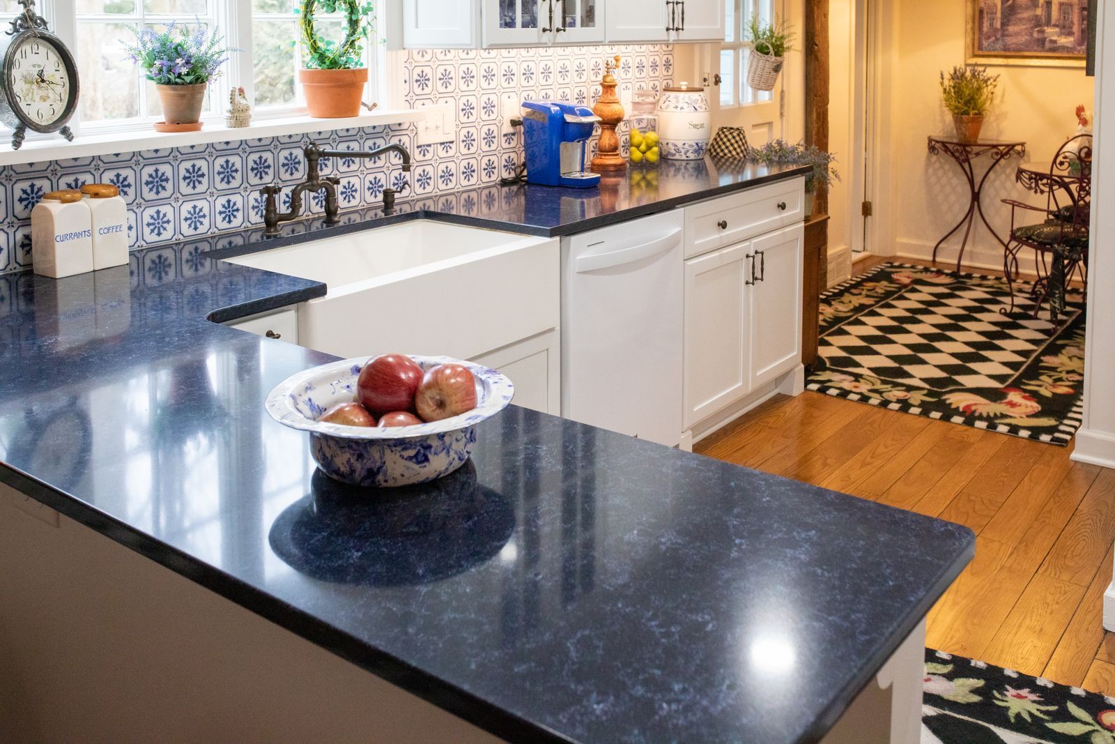 Kitchen with dark blue countertop, white sink, and white cabinets. Fruit bowl on the counter.