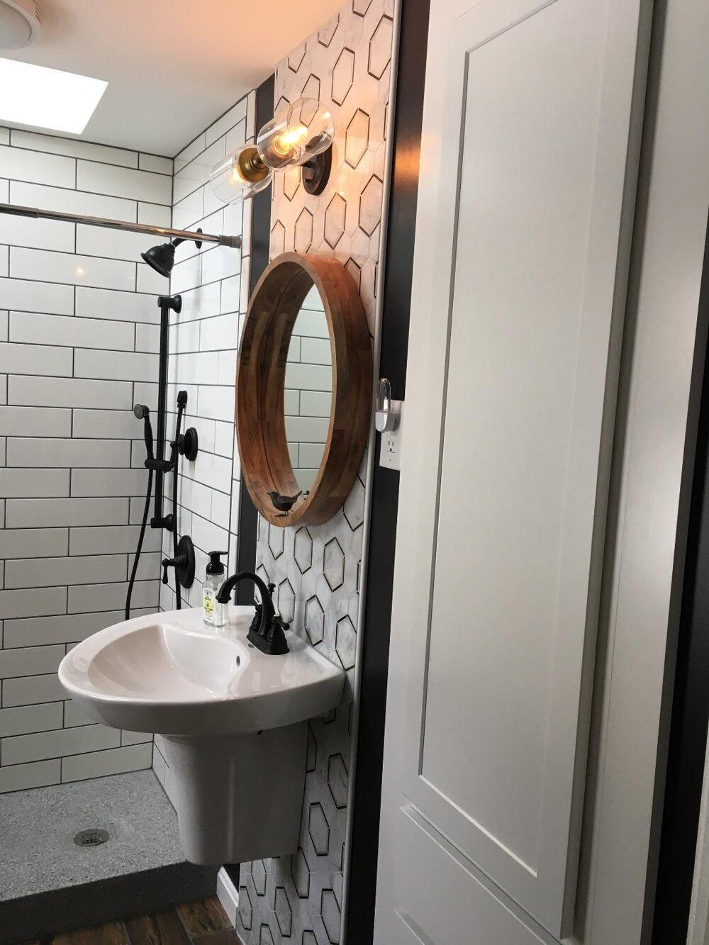 Small bathroom with white pedestal sink, black fixtures, and patterned tile.