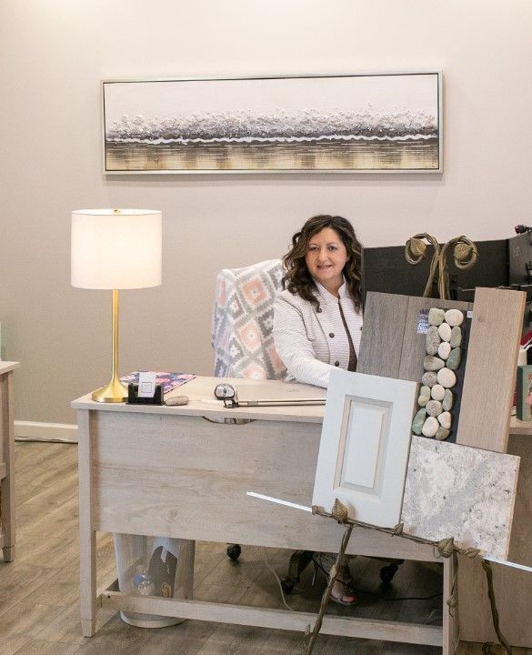 Woman at desk in office; samples and lamp on display.
