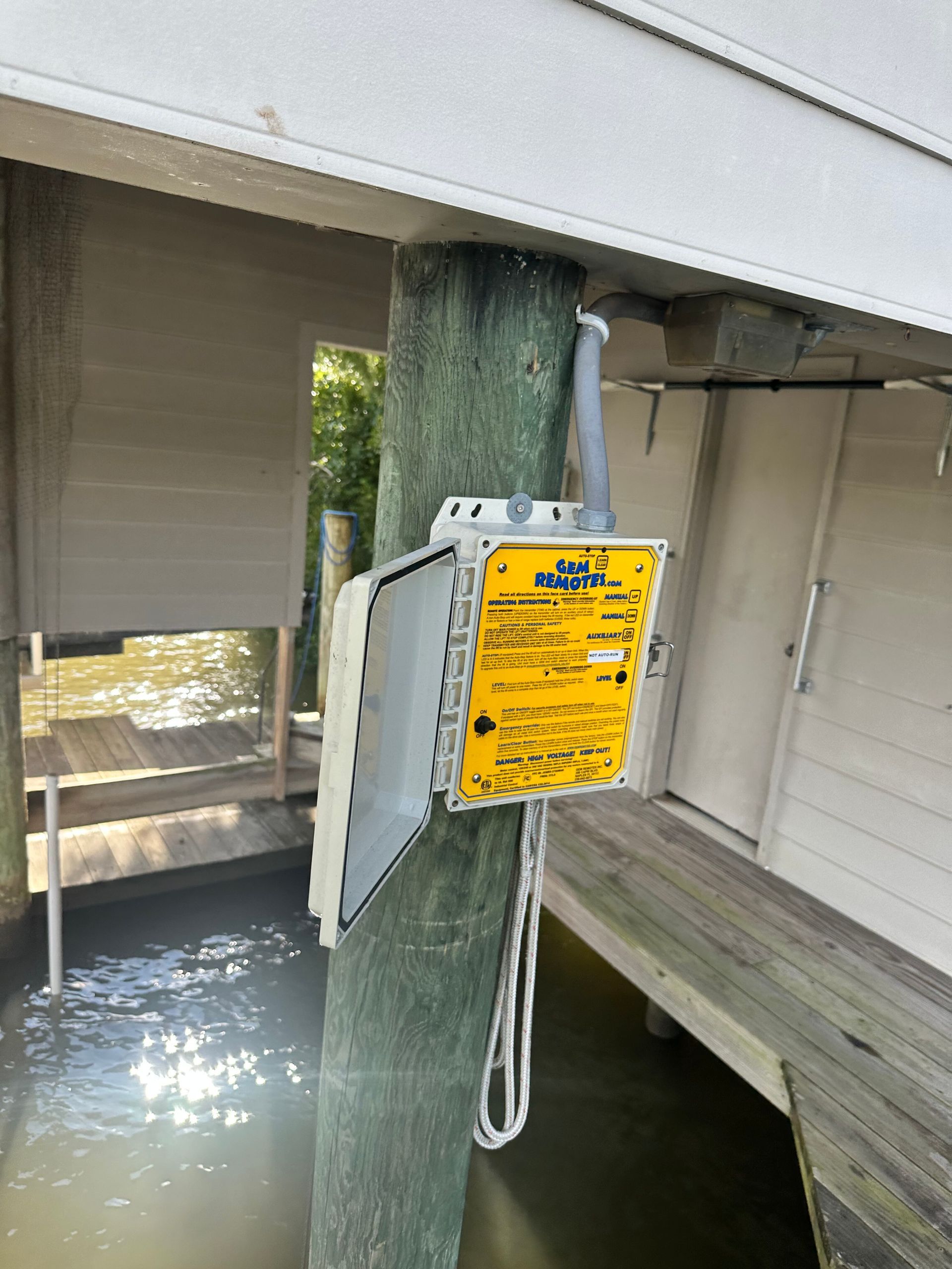 Outdoor electrical box on a wooden post with an antenna, next to water and a dock.