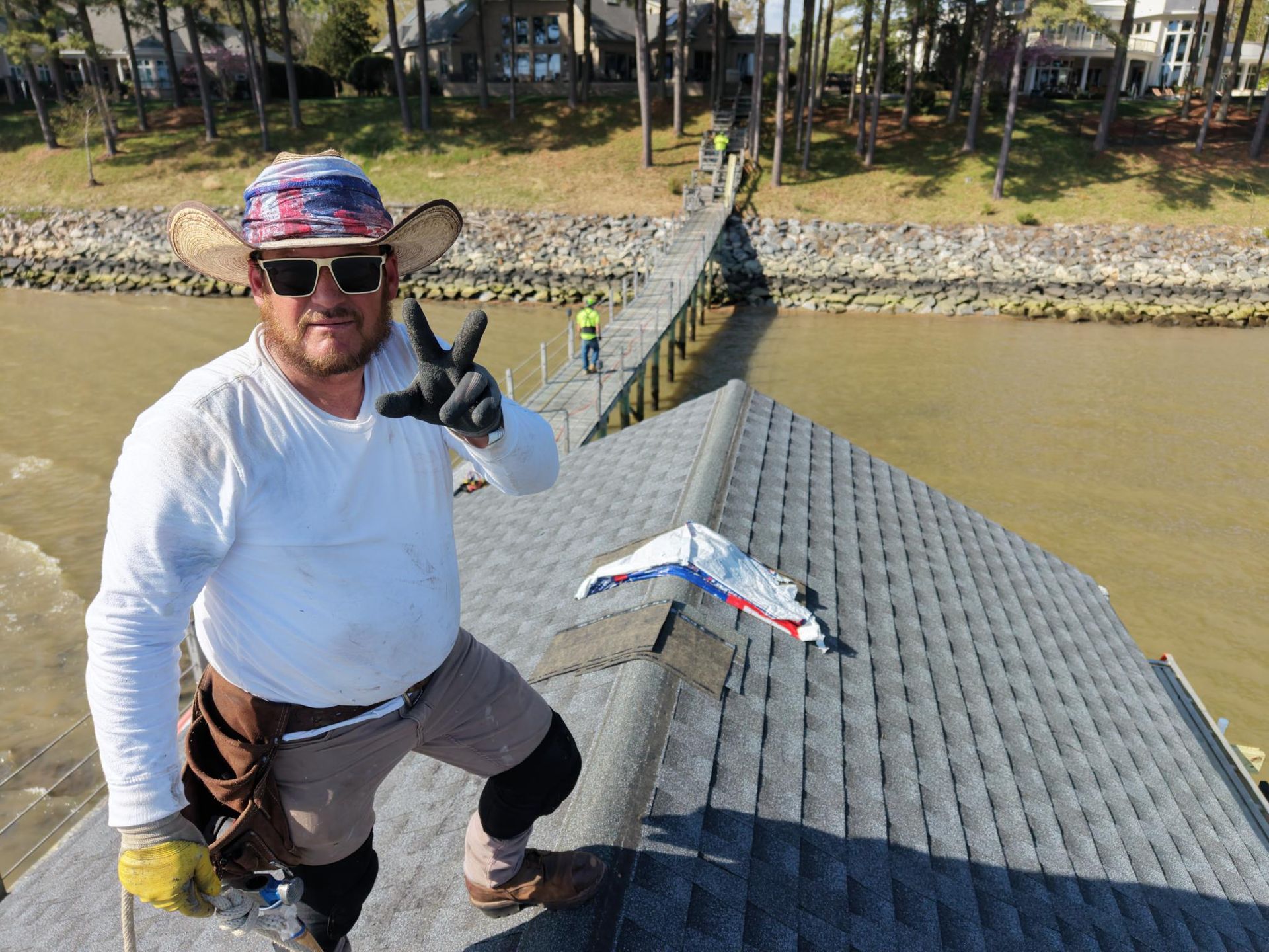 Smiling person on a dock holding a fish, with a fish laid on the dock nearby.