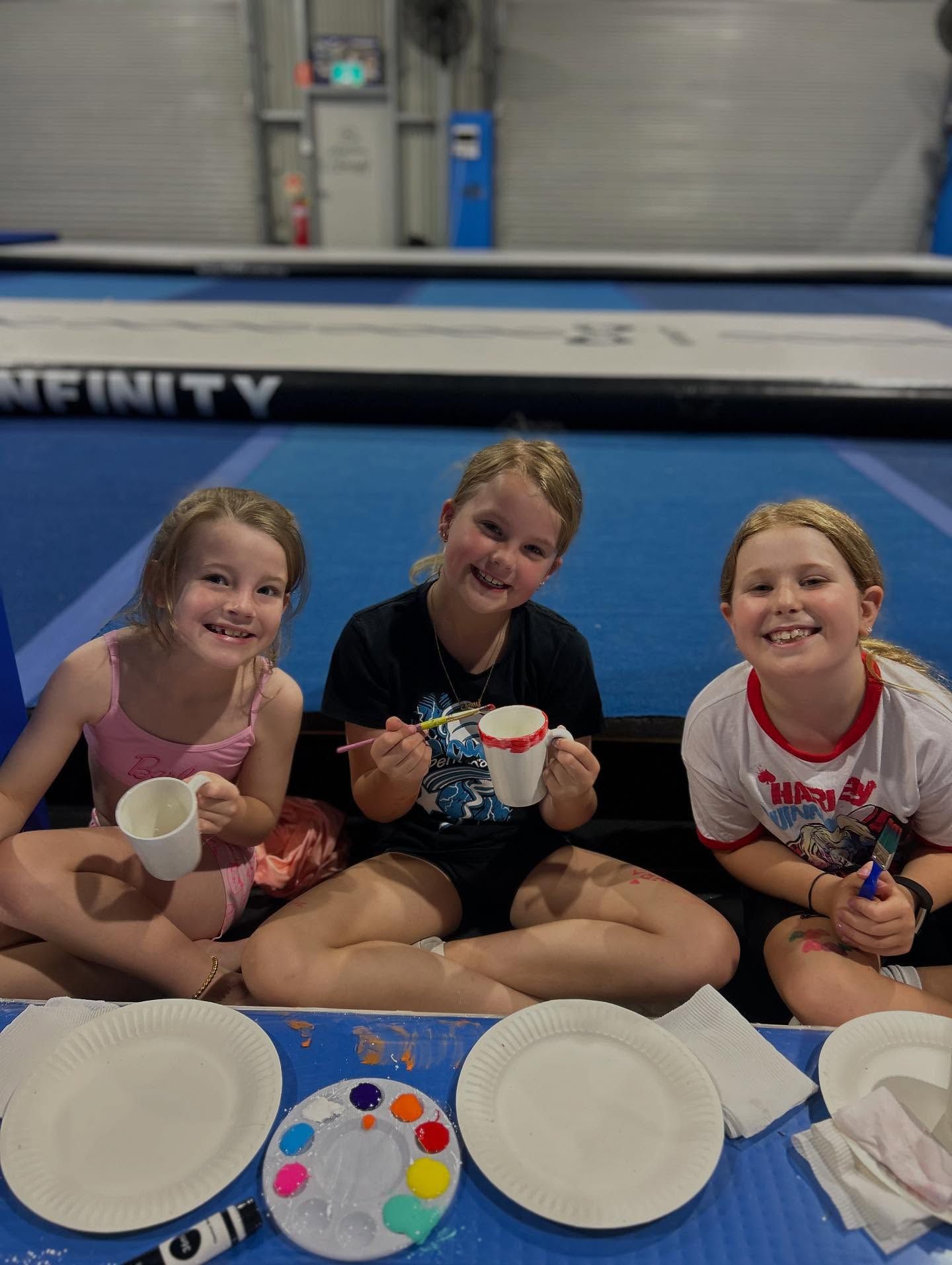 Three Smiling Children Painting Mugs on a Blue Floor in a Gym — iDance Performance Co In Medowie, NSW