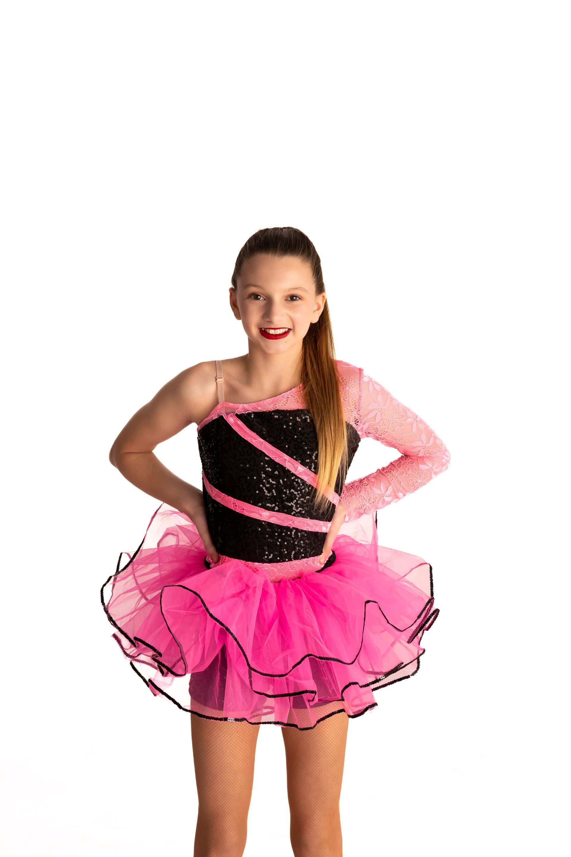 Girl in pink tutu and black leotard poses with hands on hips, smiling, against white background — iDance Performance Co In Medowie, NSW