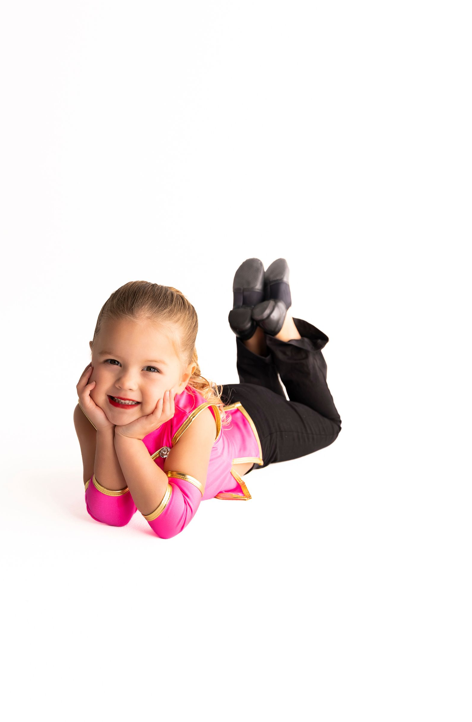 Young Child in Pink and Black Outfit Smiles While Lying on Floor — iDance Performance Co In Medowie, NSW