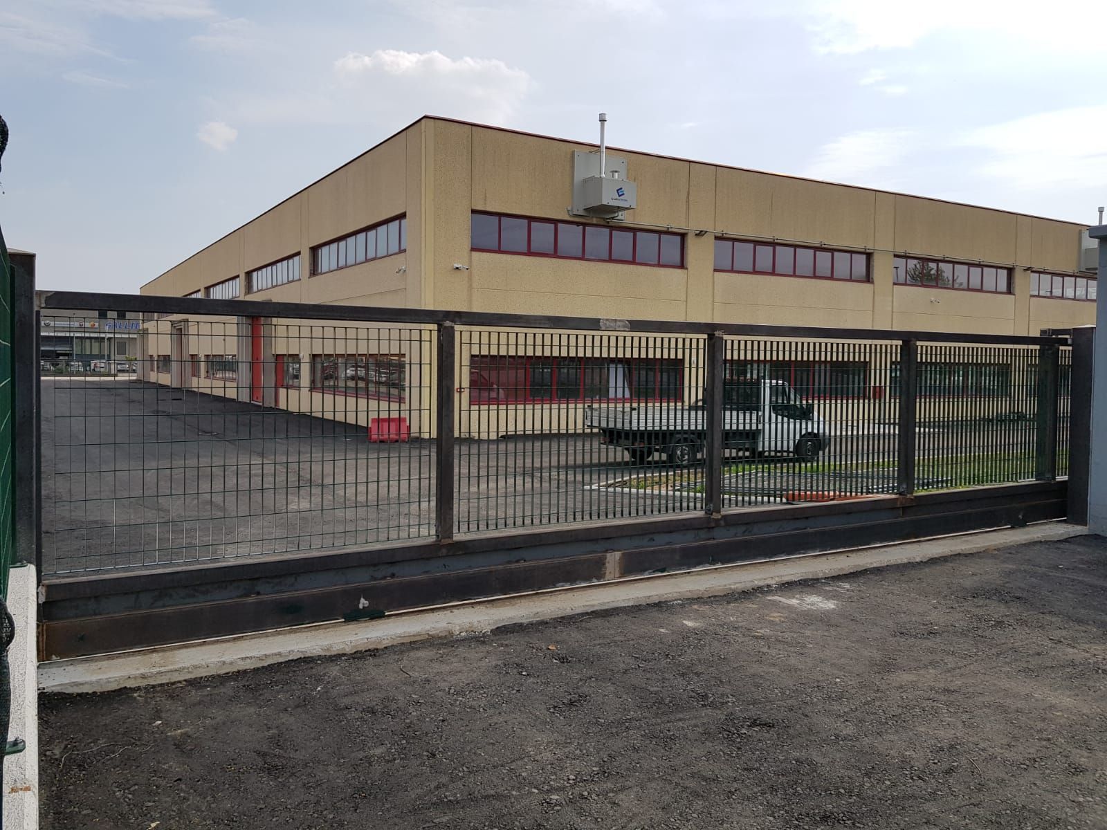 Un grande edificio con una recinzione intorno e un camion parcheggiato di fronte