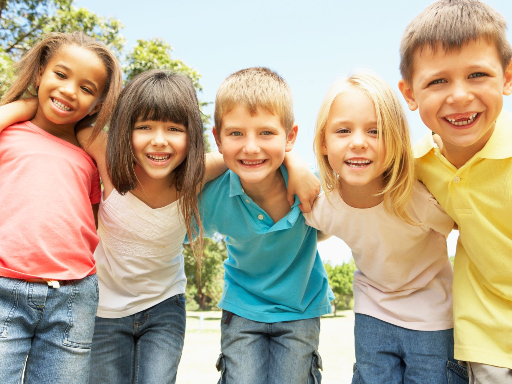 Five children smiling and leaning together outdoors on a sunny day