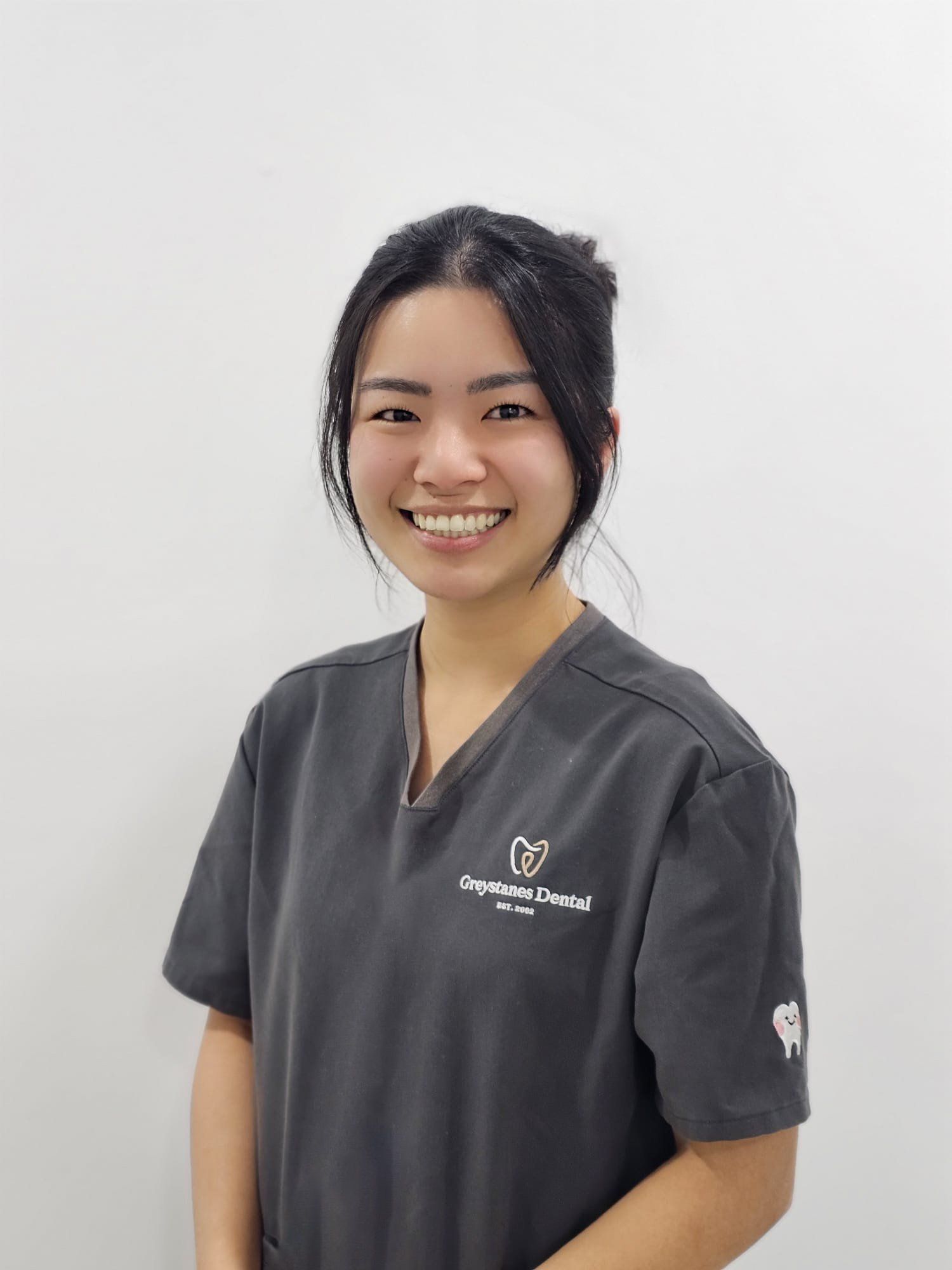 A woman in a scrub top is smiling for the camera. A woman in a scrub top is smiling for the camera.