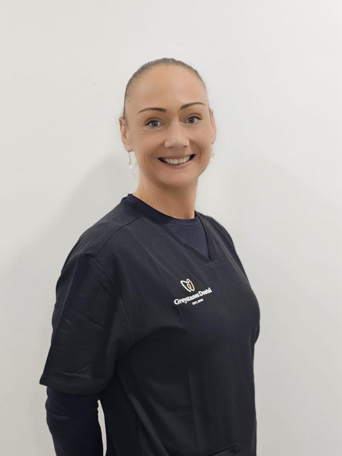 A woman in a black scrub top is smiling for the camera. A woman in a black scrub top is smiling for the camera.