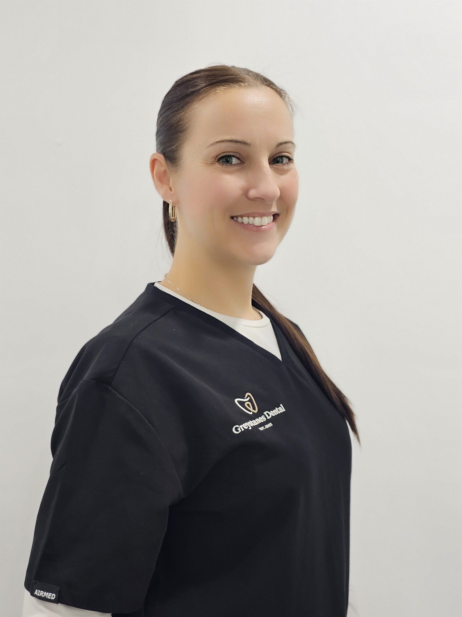 A woman in a black scrub top is smiling for the camera. A woman in a black scrub top is smiling for the camera.