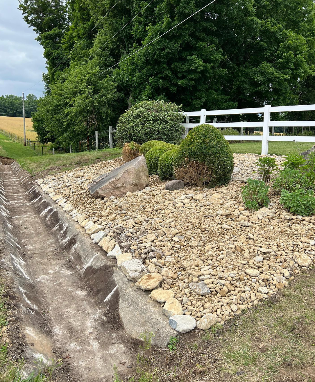 A rock garden with a white fence in the background.