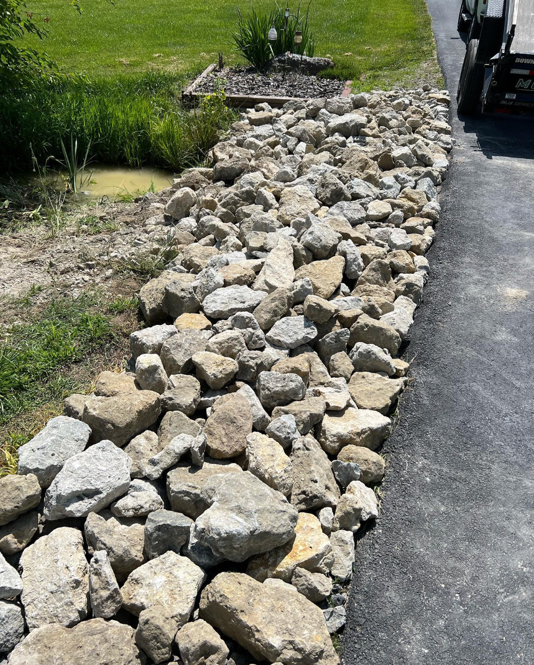 A pile of rocks is sitting on the side of a road.