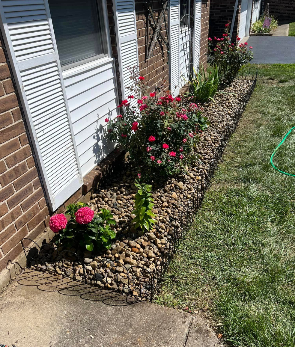 A brick house with a lawn and flowers in front of it.