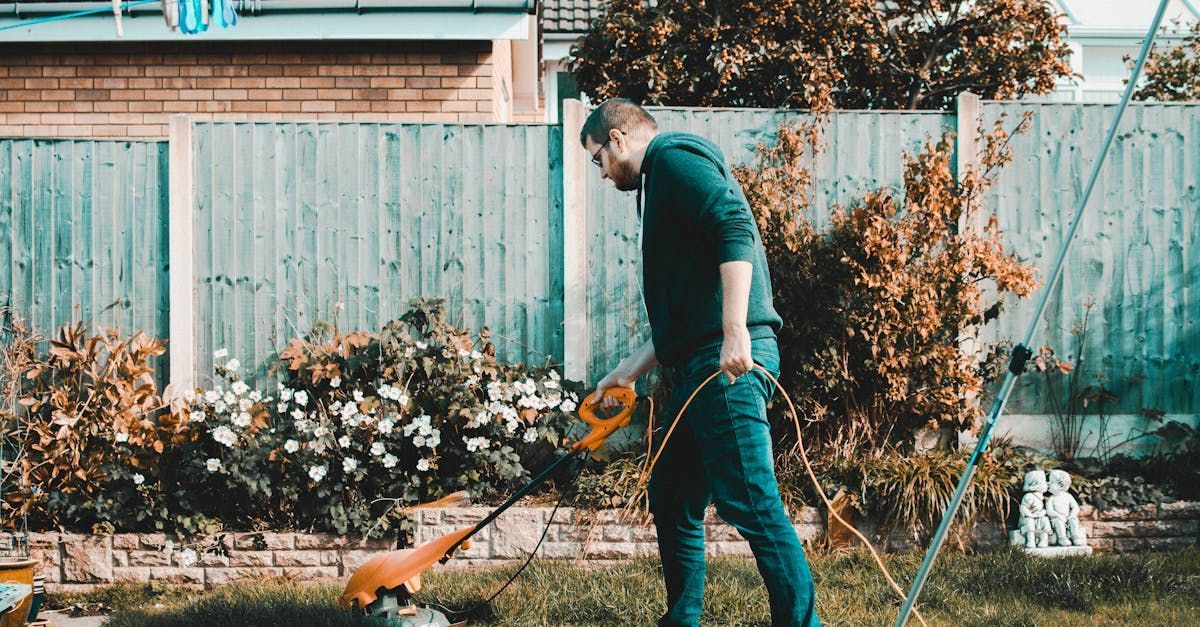 A man is using a lawn mower to cut the grass in his backyard.