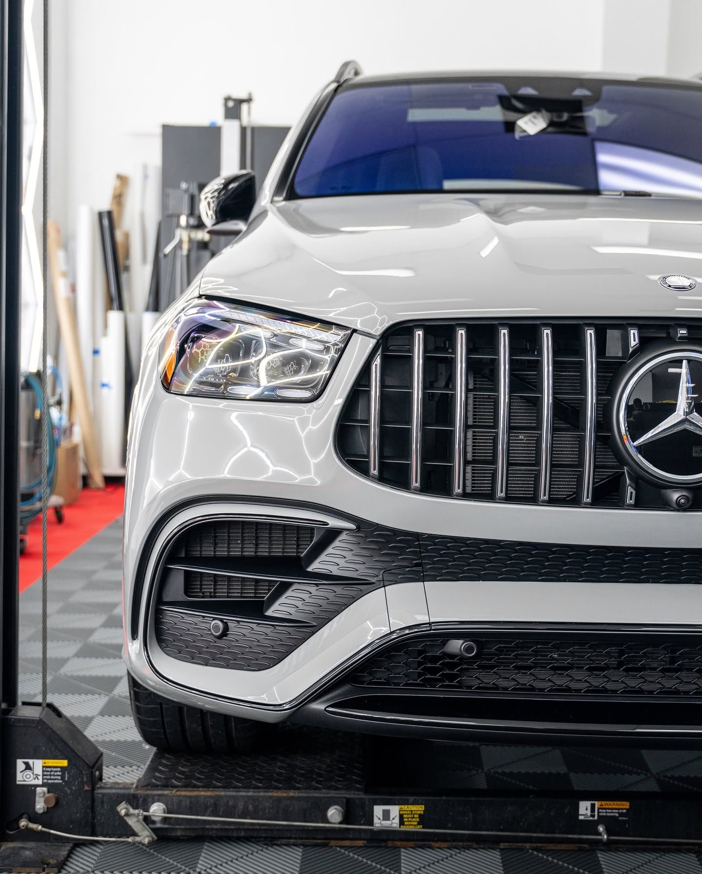 Silver Mercedes SUV on a lift in an auto shop, front view with grille and headlights visible