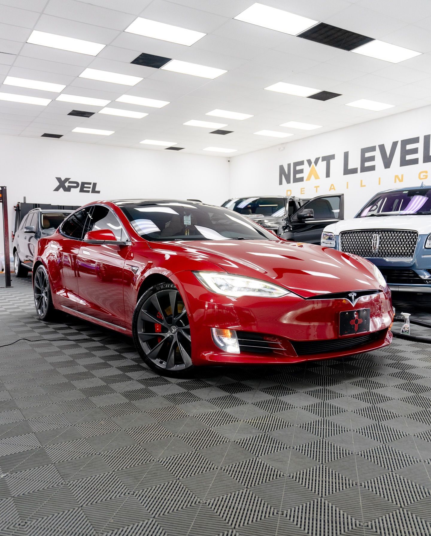 Red Tesla car in a detailing shop.