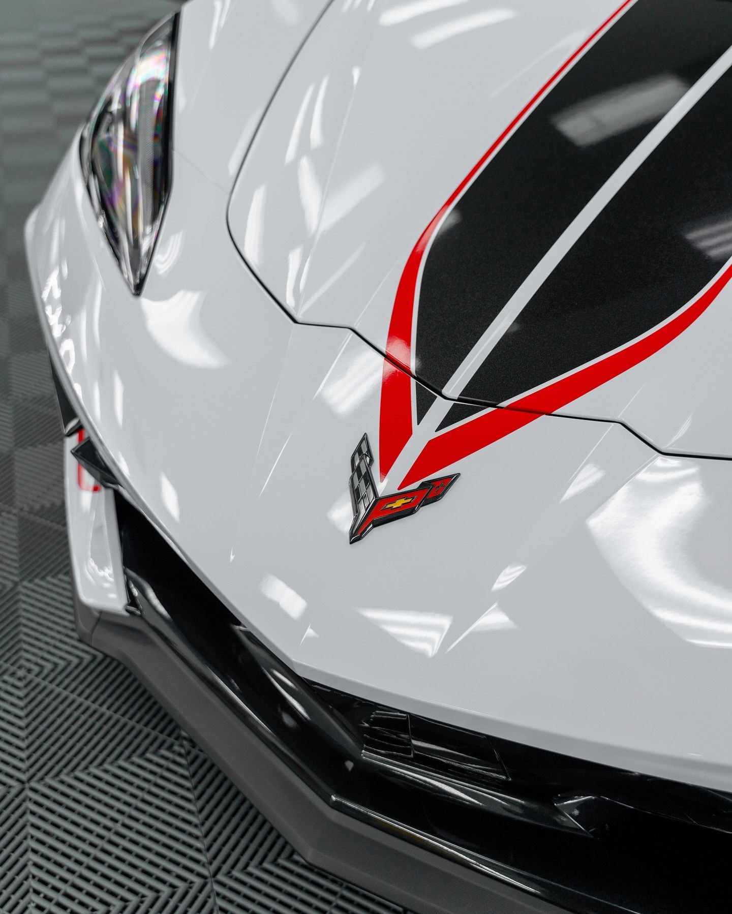 White sports car front with black and red racing stripes. Chevrolet logo.