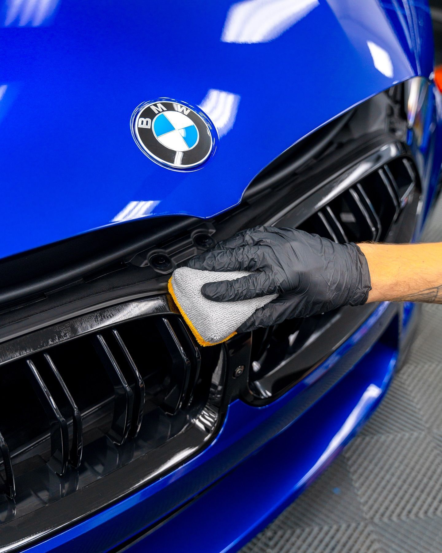 A person is polishing the hood of a car with a sponge.