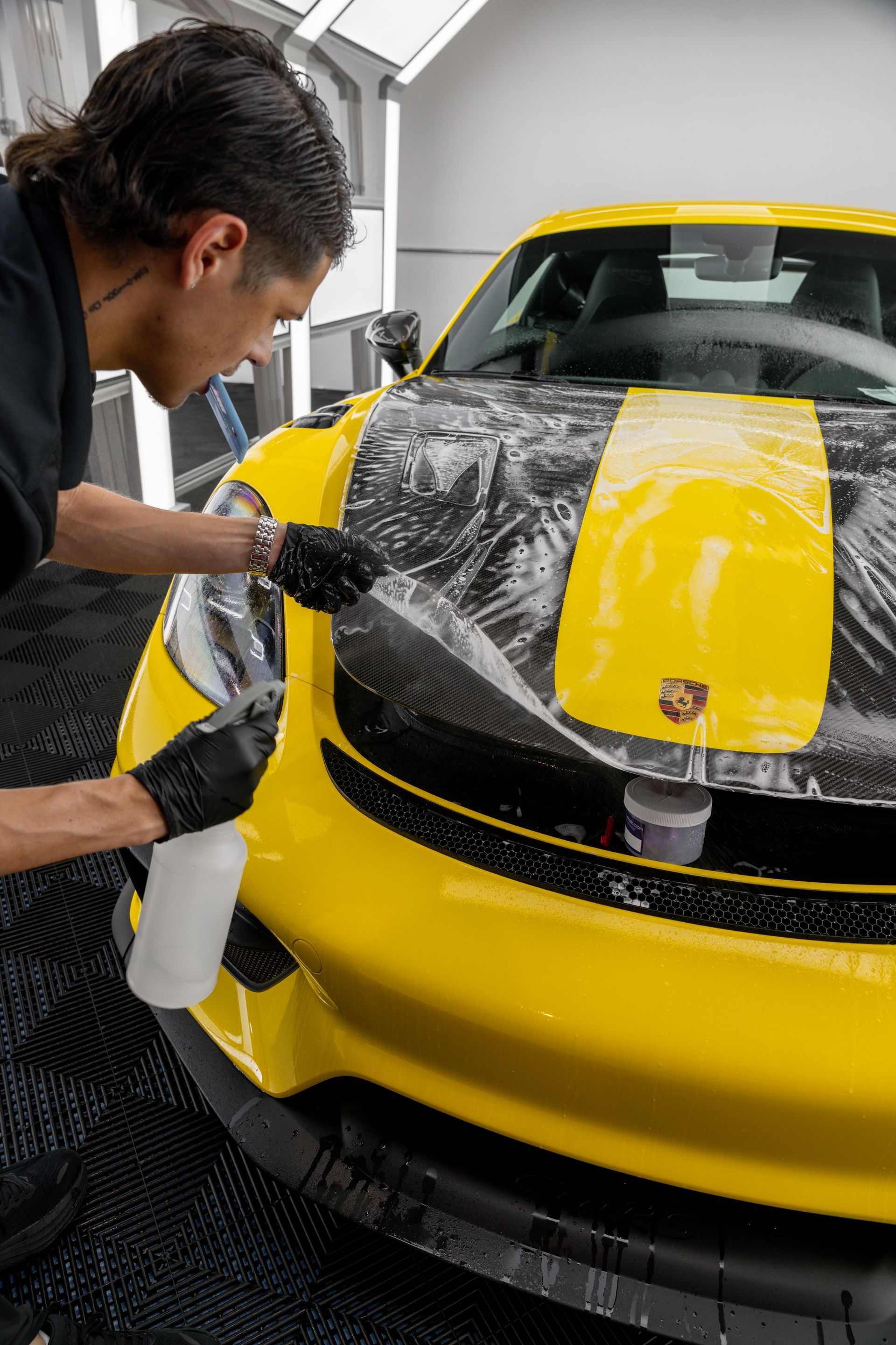 A man and a woman are cleaning a car in a garage.