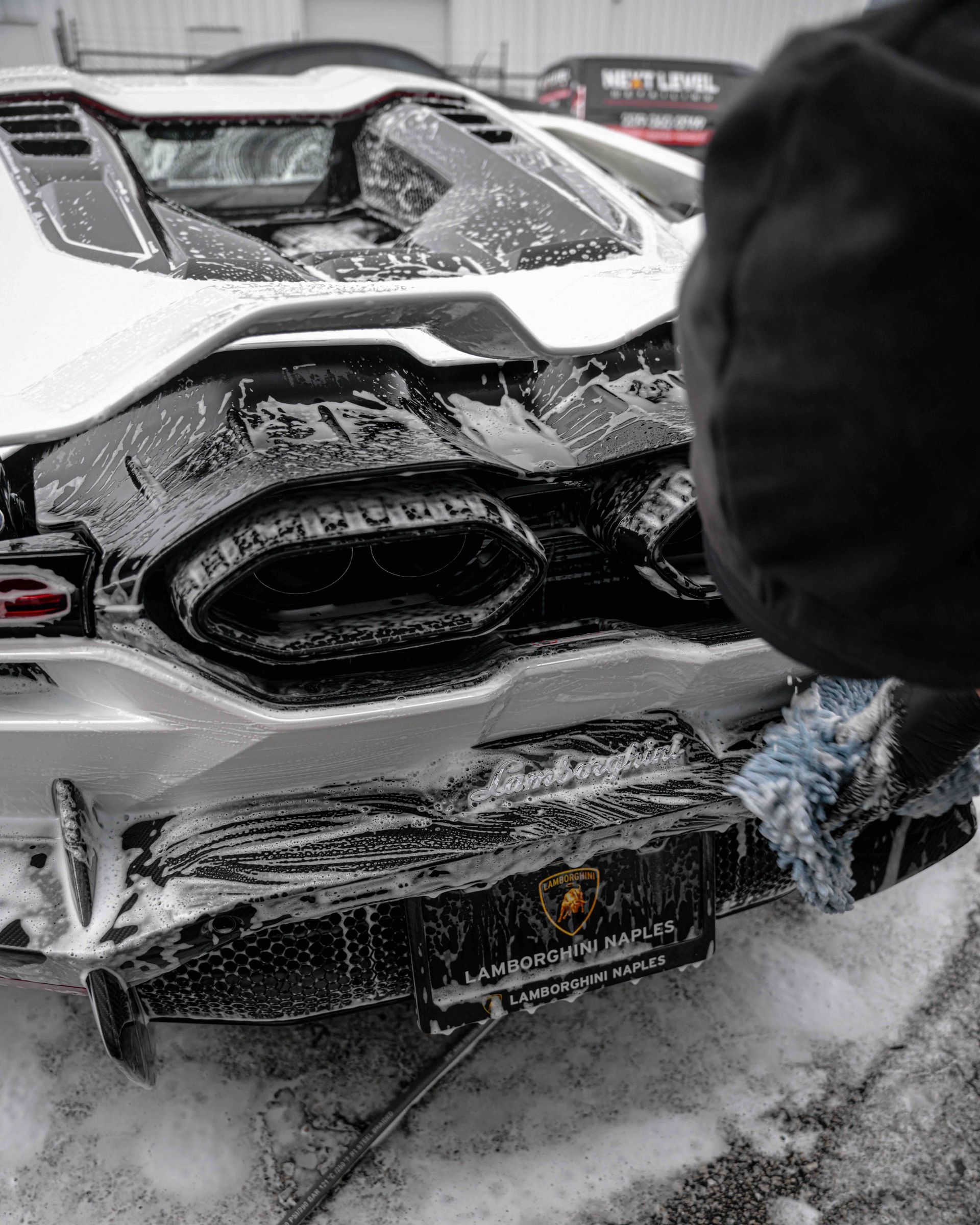 A person is cleaning a damaged sports car in the snow.