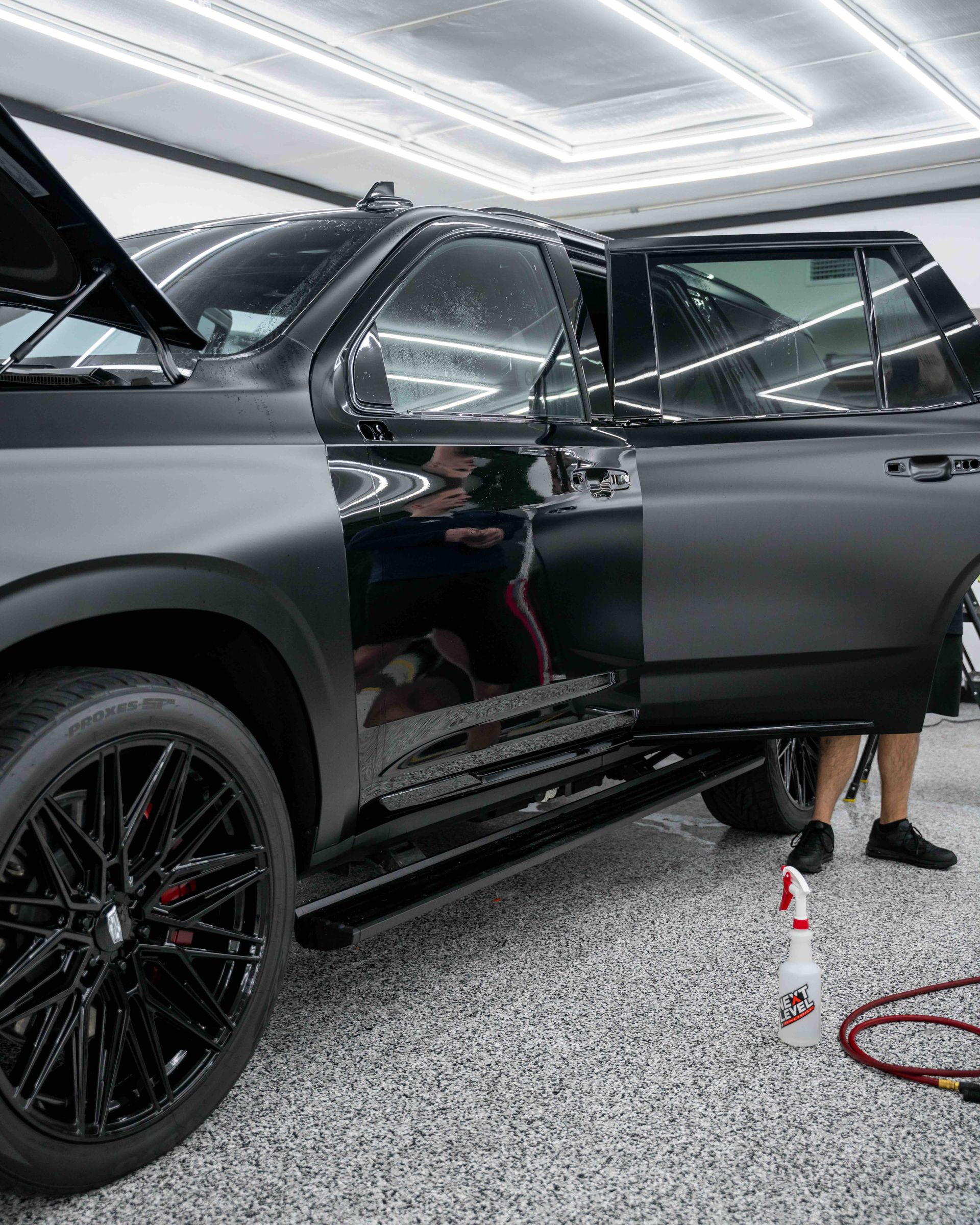 A black suv is parked in a garage with the door open.