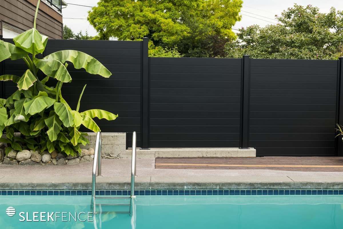 A black fence surrounds a swimming pool with stairs leading to it.