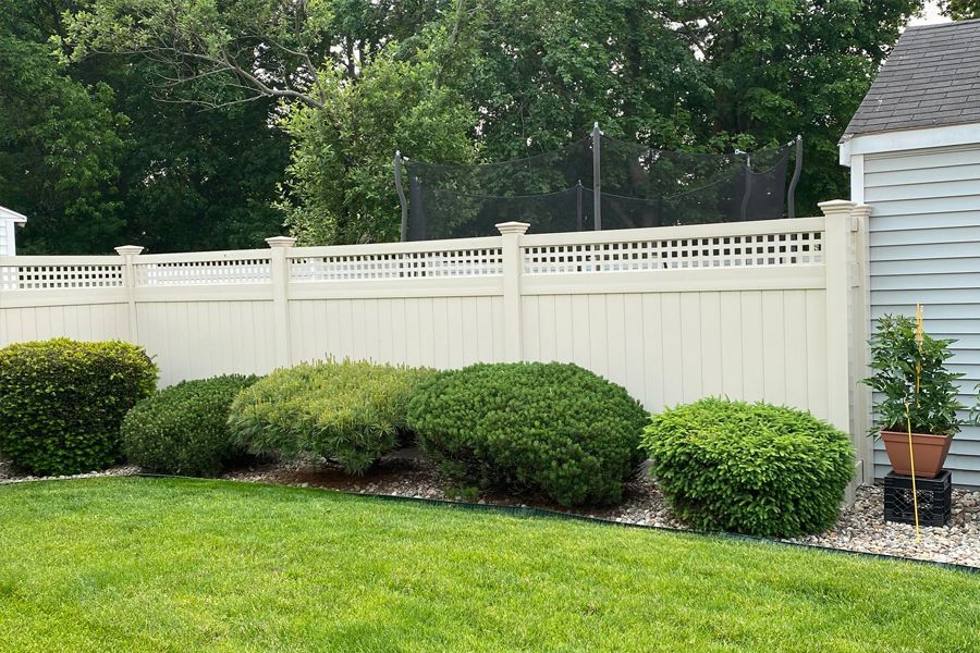 A white fence surrounds a lush green lawn in a backyard.