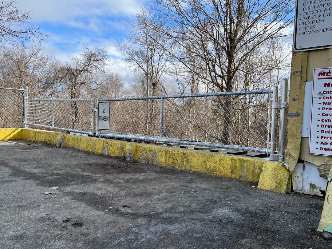 A parking lot with a yellow curb and a metal fence.