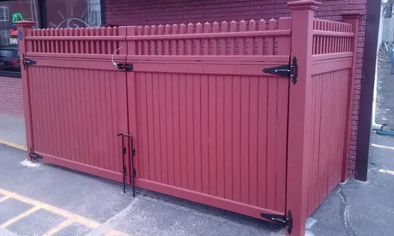 A red fence is sitting in front of a brick building.